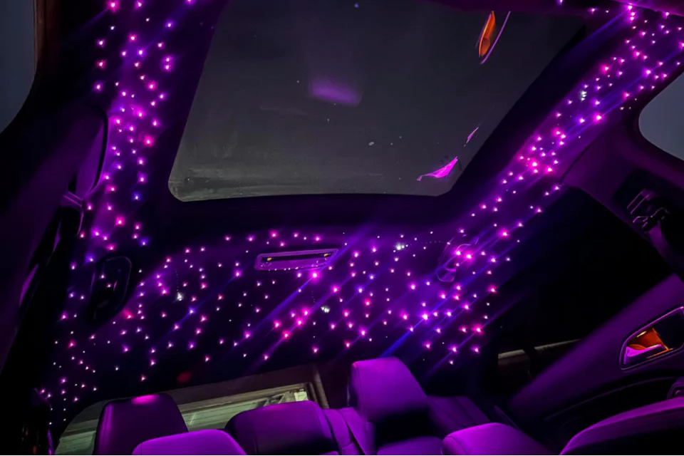 Car interior with purple LED lights on the dashboard and ceiling.